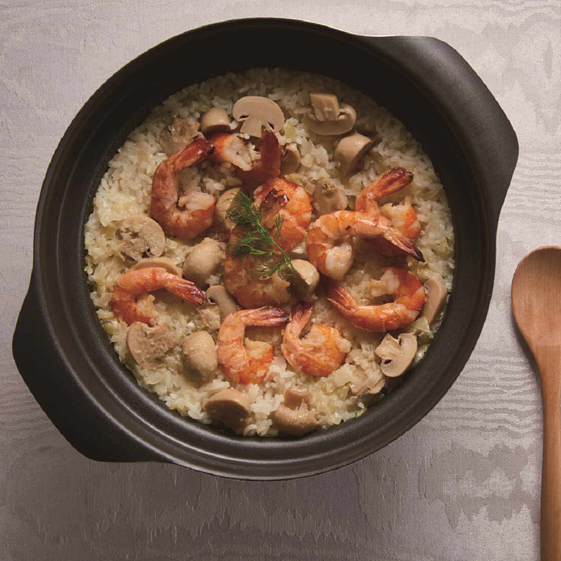 Cooked rice with sautéed shrimp and mushrooms in a black Donabe ceramic cooking pot