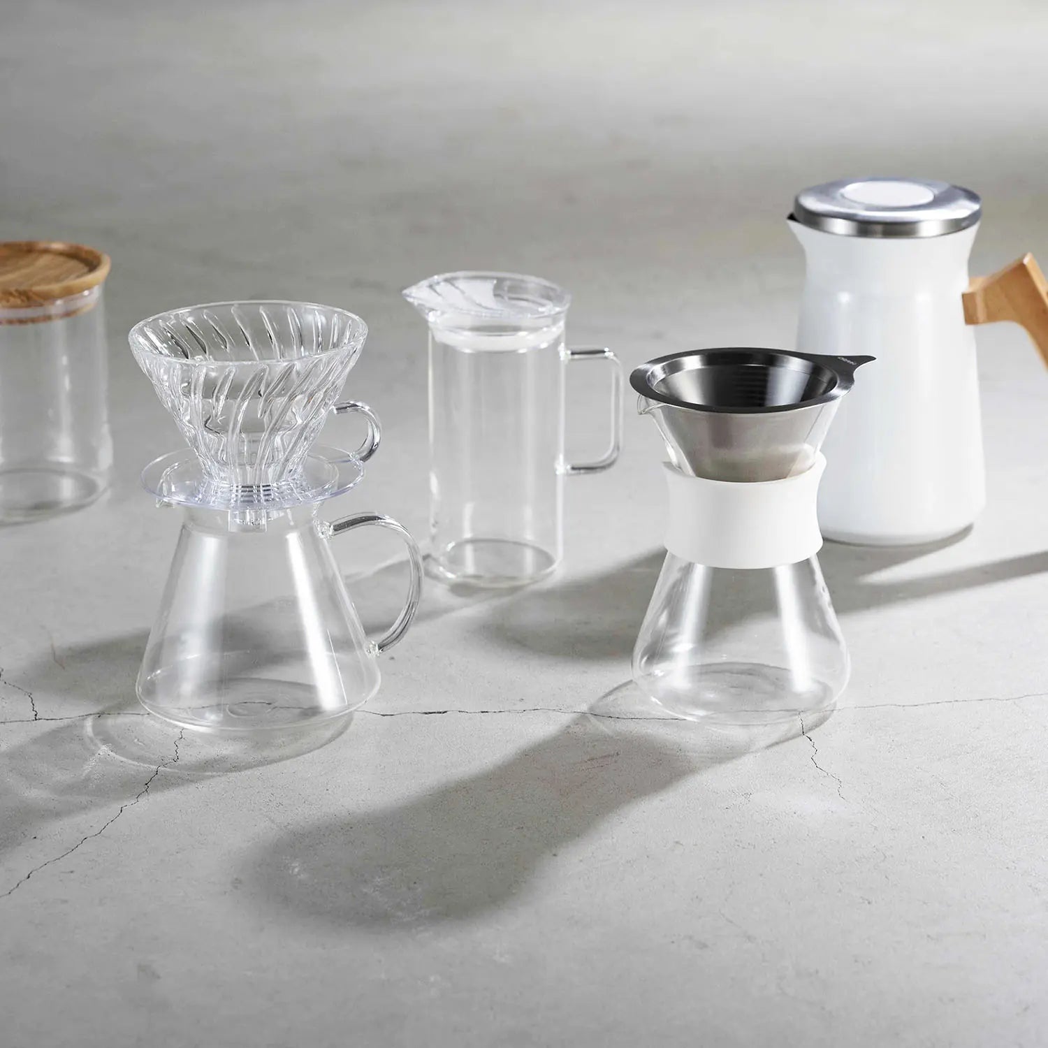 Collection of Hario glass coffee and tea brewing equipment including pour-over dripper, server, and storage containers.