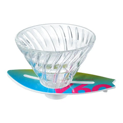 V60 dripper on teal-to-magenta ombre surfboard base against white background.