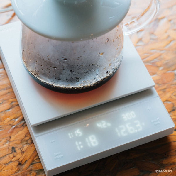 Close-up of glass carafe sitting on white Polaris scale showing liquid level and weight