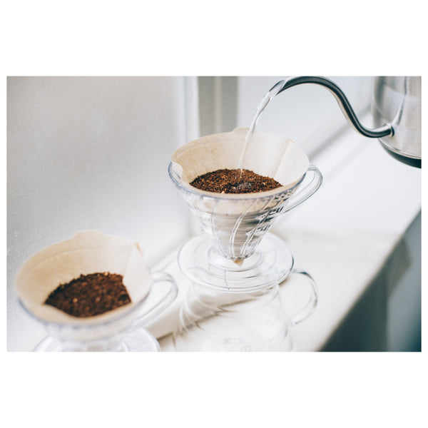 Hot water pouring into V60 dripper filled with coffee grounds and white filter.