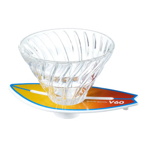 V60 dripper positioned on blue-to-orange surfboard base with striped design detail.
