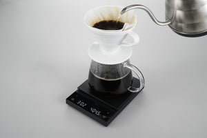 Black Polaris coffee scale with white ceramic dripper and filter during pour-over brew