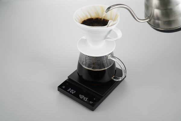 Black Polaris coffee scale with white ceramic dripper and filter during pour-over brew