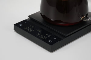 Dark glass carafe of brewed coffee sitting on black Polaris scale with digital display