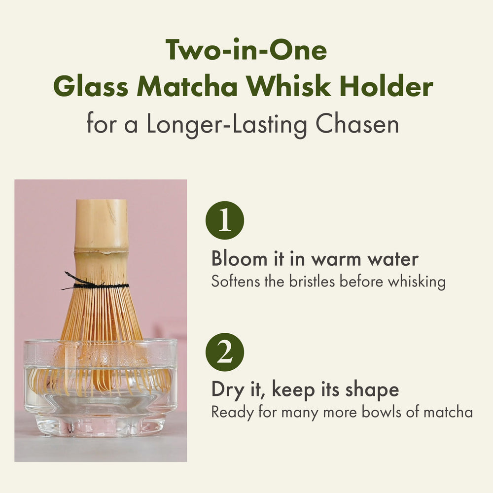 Bamboo matcha whisk resting in clear glass bowl next to tall glass with layered green and white matcha mixture on pink