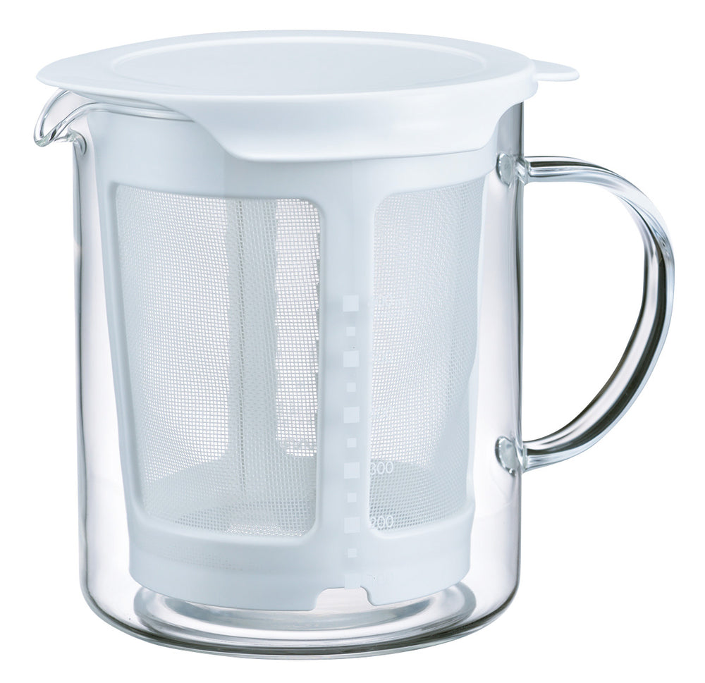 Glass pitcher filled with pale yellow broth next to removable mesh strainer basket containing tea bag.