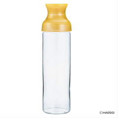 Single empty cold brew carafe with yellow cap against white background.