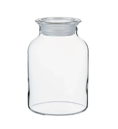 Empty cylindrical glass storage jar with flat lid, viewed from front against white background.