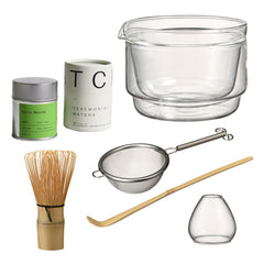 Matcha set components arranged in organized layout showing two matcha powder containers, bamboo whisk, glass mixing bowl