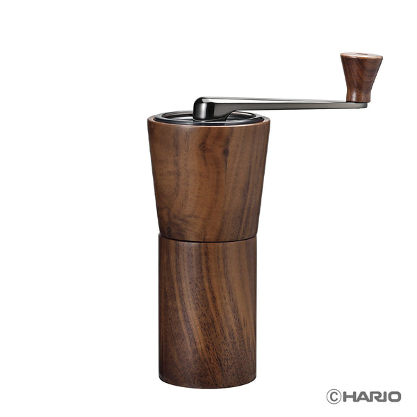 Walnut wood manual coffee grinder with black metal top and hand crank on white background.