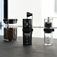 Three black Hario Smart G Pro coffee mills displayed side by side with coffee beans visible inside.