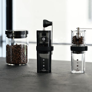 Three black Hario Smart G Pro coffee mills displayed side by side with coffee beans visible inside.