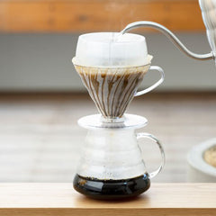 Hario V60 Hario V60 drip cone with paper filter in glass carafe showing dark coffee brewed