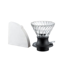 Glass V60 dripper with black base and white paper filter displayed next to filter package.