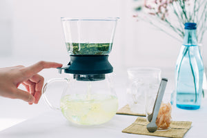 Close-up of water pouring into Largo dripper's upper chamber filled with tea leaves and filter.