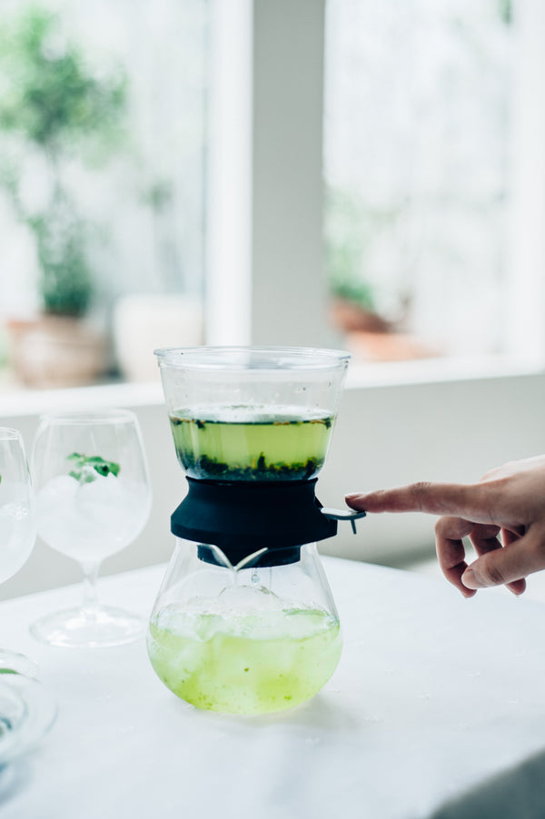 Largo tea dripper in use, showing pale green matcha tea being filtered from upper chamber to lower vessel.