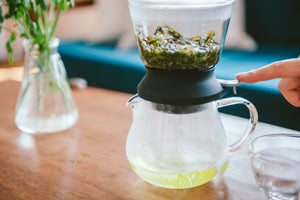 Largo dripper positioned above glass server pouring steeped tea into collection vessel below.