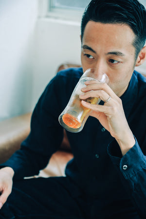 Close-up of man drinking layered beer from glass showing golden and white layers