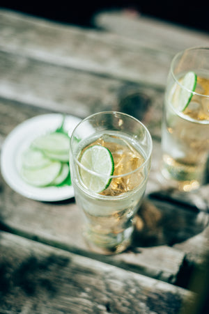Close-up of lime wedge floating in sparkling water inside transparent double-walled glass on wooden surface