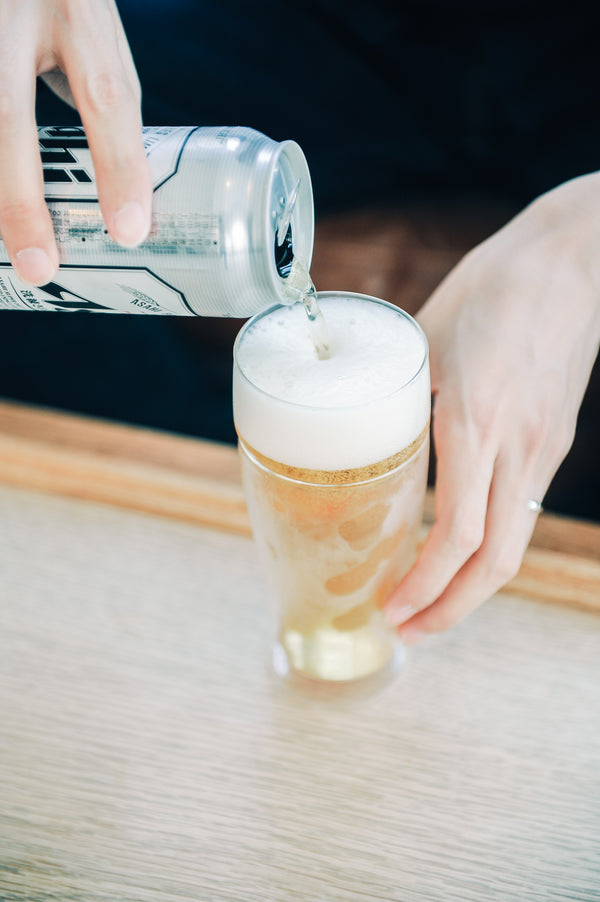 Pitcher dispensing white foam into tall glass showing distinct golden and white separation