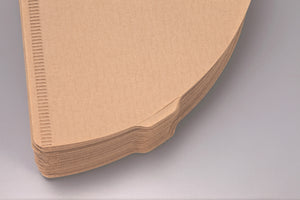 Edge view of stacked white V60 paper filters showing ribbed texture.