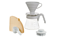 Hario V60 02 complete set laid out showing gray ceramic dripper, glass carafe with measurement markings, wooden filter