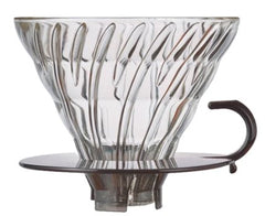 Clear glass V60 dripper with ribbed cone pattern and black handle, viewed from front angle.