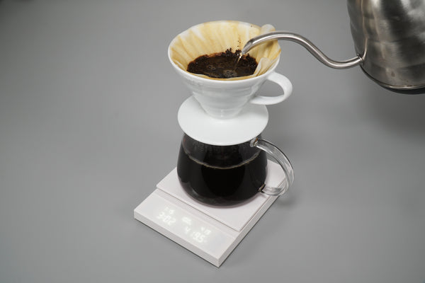 Polaris scale with ceramic dripper dripping brewed coffee into glass carafe