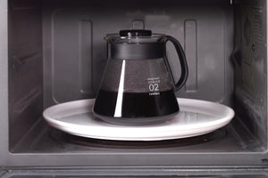 Hario V60 microwave server model 02 positioned on white plate inside microwave oven