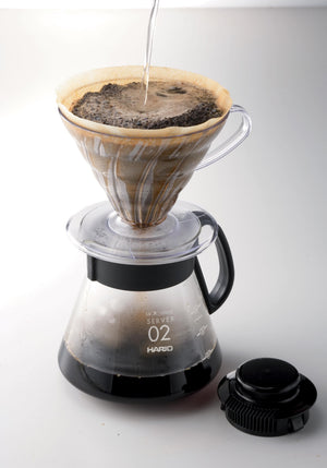 Hario V60 microwave server with coffee dripper pouring hot water into glass carafe filled with ground coffee