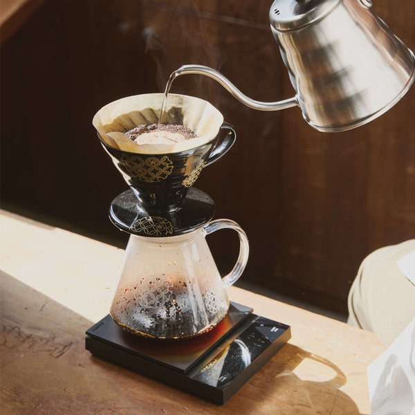 Pouring hot water into V60 dripper with filter during pour-over brewing