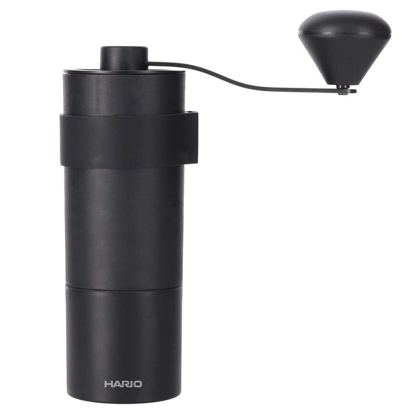 Black cylindrical Zebrang coffee grinder with attached hand crank and conical burr system, white background