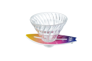 V60 dripper centered on yellow-to-magenta gradient surfboard stand, minimalist white background.
