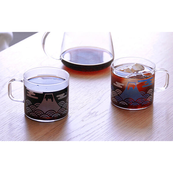 Three glass mugs with Mount Fuji designs in different color variations, filled with beverages.