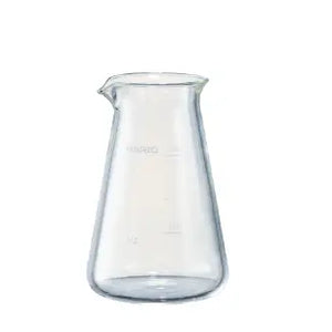 Empty clear glass conical pitcher with measurement marks and pouring spout, shown against white background.
