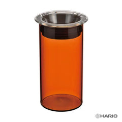 HARIO Colors canister with amber glass and metal lid filled with orange-red brewed coffee