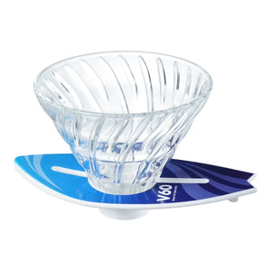 V60 dripper sitting on cyan-to-navy blue surfboard stand, side angle view.