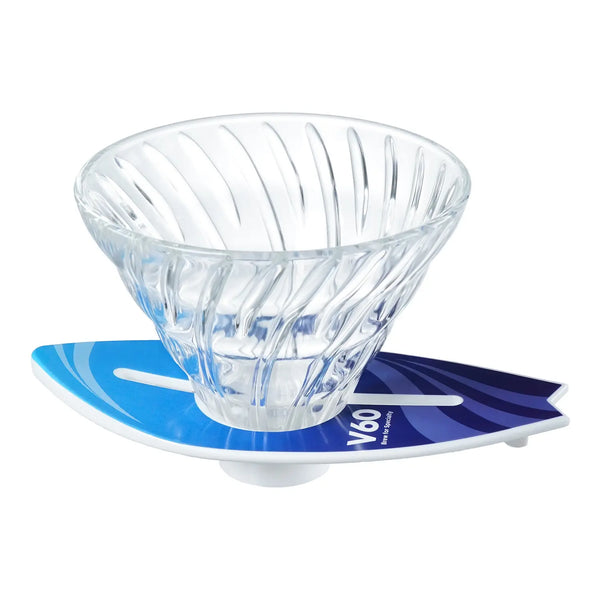 V60 dripper sitting on cyan-to-navy blue surfboard stand, side angle view.