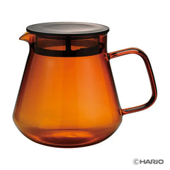 Empty amber glass carafe with black mesh filter band and gray lid.